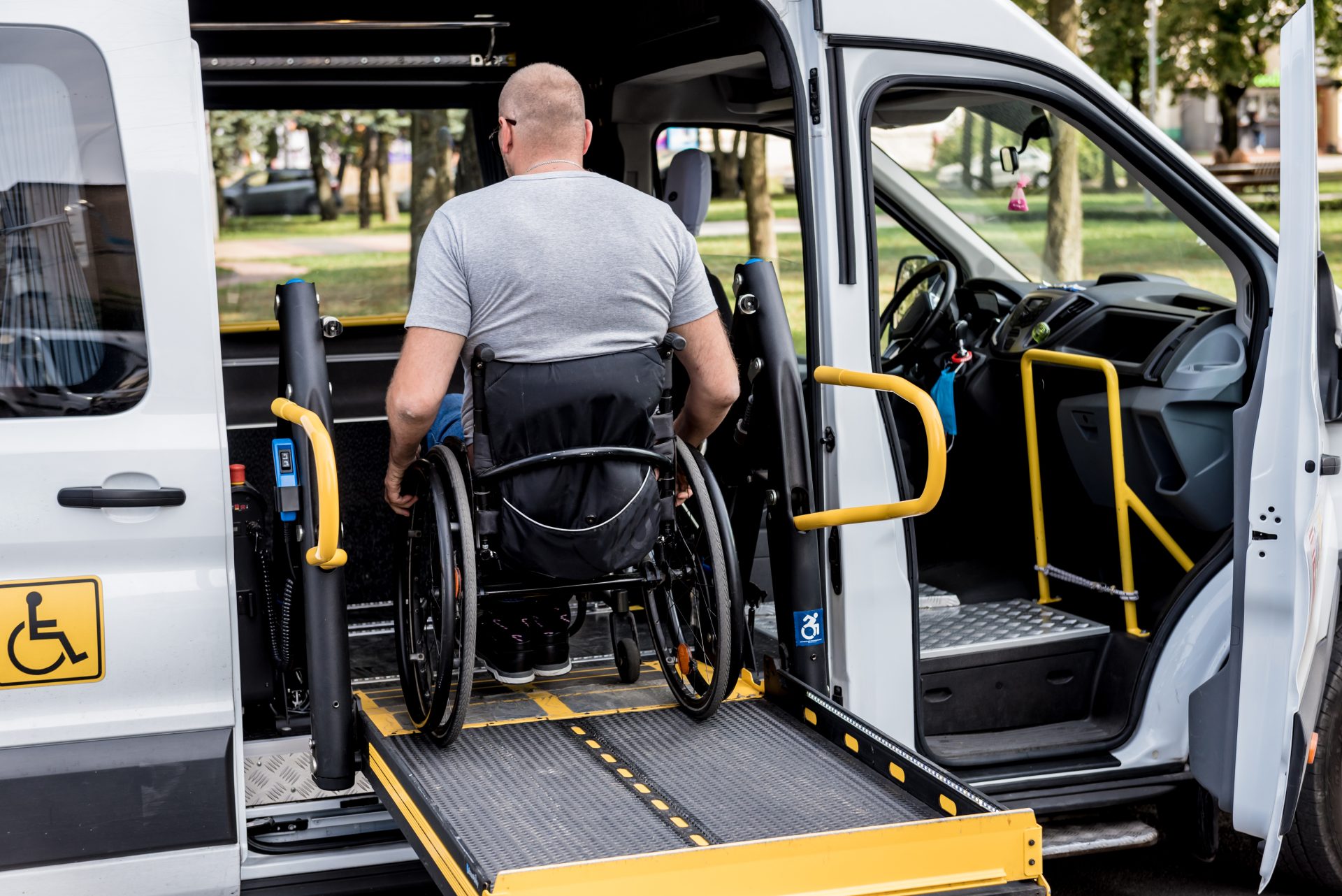 Photo d'une personne en fauteuil motorisé utilisant un ascenseur sur le côté un véhicule adapté